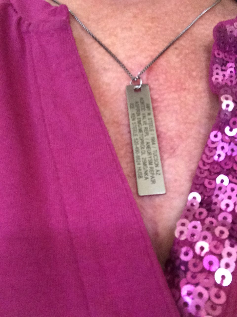 A Close-up of the back of my medical alert necklace with my information. I really like it because it somewhat covers my scar, plus it doesn't look like a medical alert id. The company is RoadID.